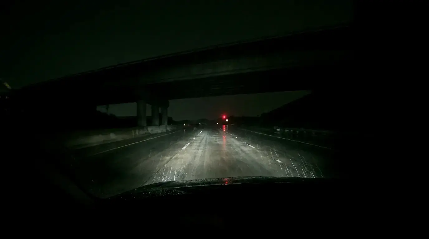 An empty highway under an overpass at night in the rain